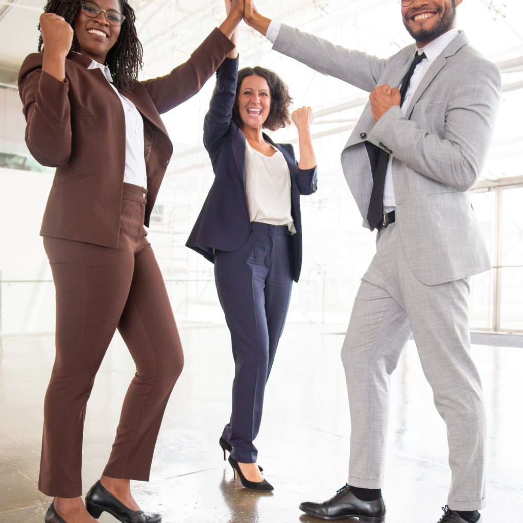 Happy business team celebrating success. Full length view of cheerful male and female business colleagues giving high five and smiling at camera. Teamwork concept